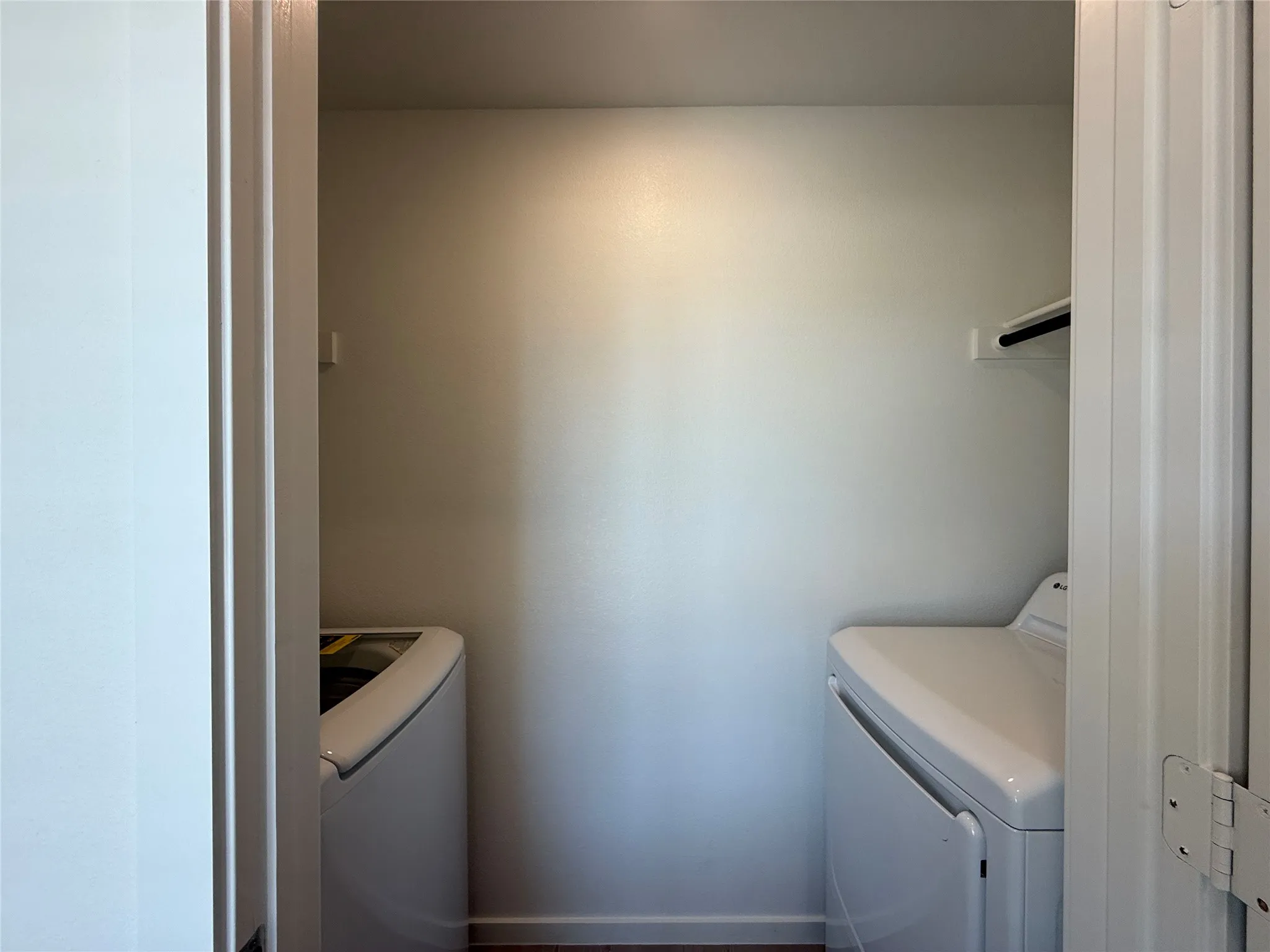 Laundry area with wood-finish flooring and a white wall shelf