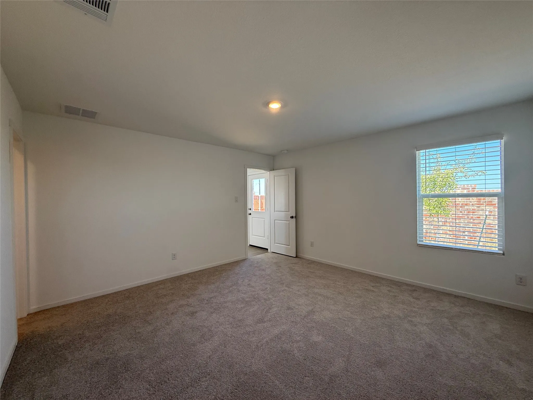 Carpeted flooring, white walls, and a window with horizontal blinds