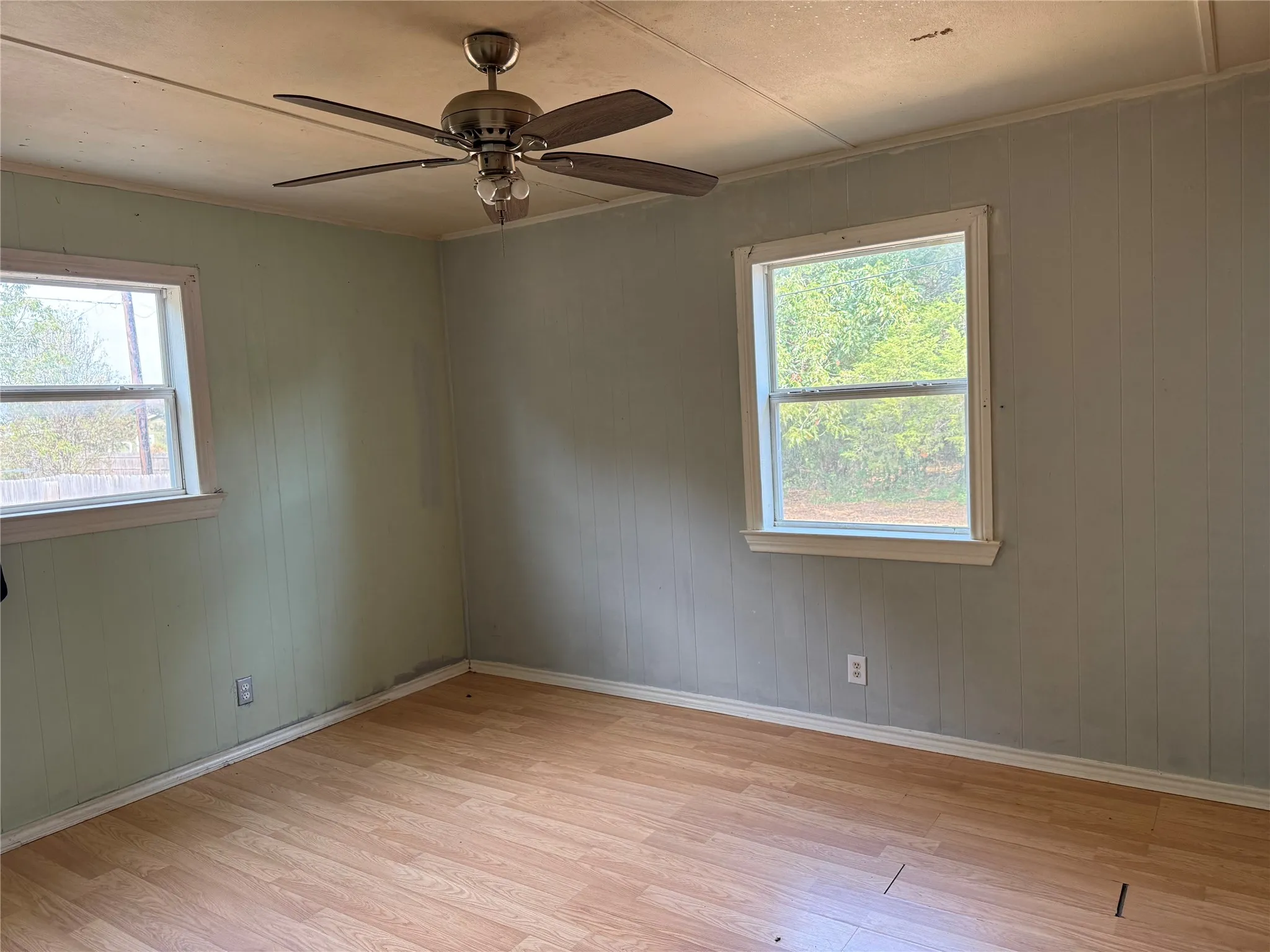 Wood-finish flooring with two windows and a ceiling fan