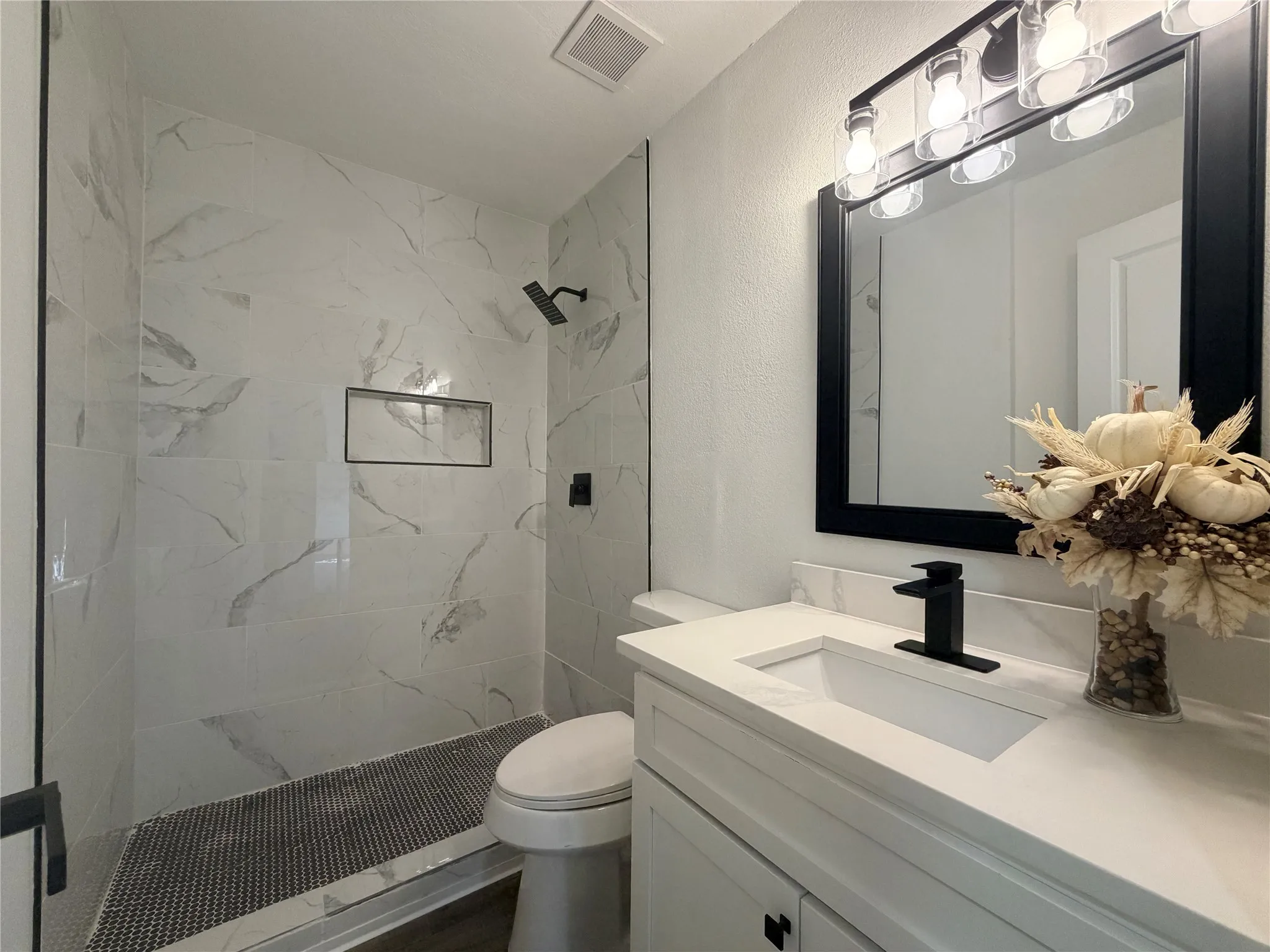 Walk-in shower with large format tile surround and integrated niche