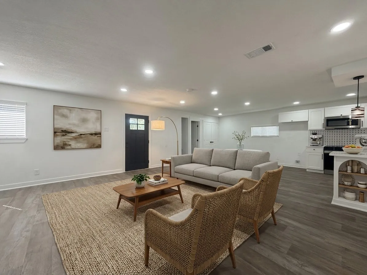 Recessed lighting throughout, wood-finish flooring, white cabinetry, dark gray entry door with glass panels, and stainless steel appliances