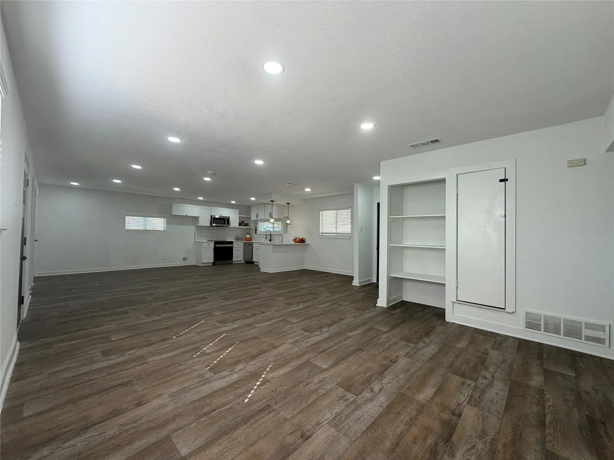 Open-concept living space featuring recessed lighting, wood-finish flooring, and built-in shelving