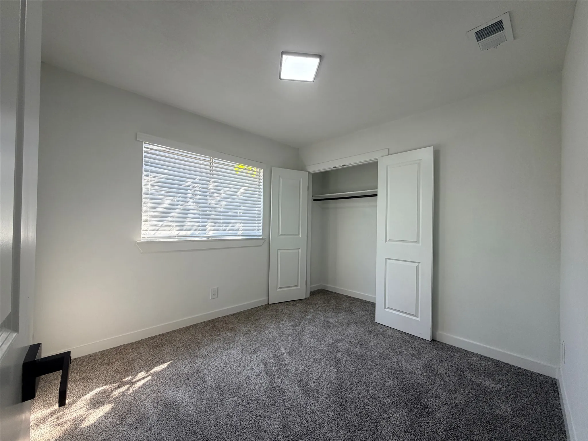 Recessed ceiling lighting, window with horizontal blinds, carpeted flooring, and a built-in closet with double panel doors