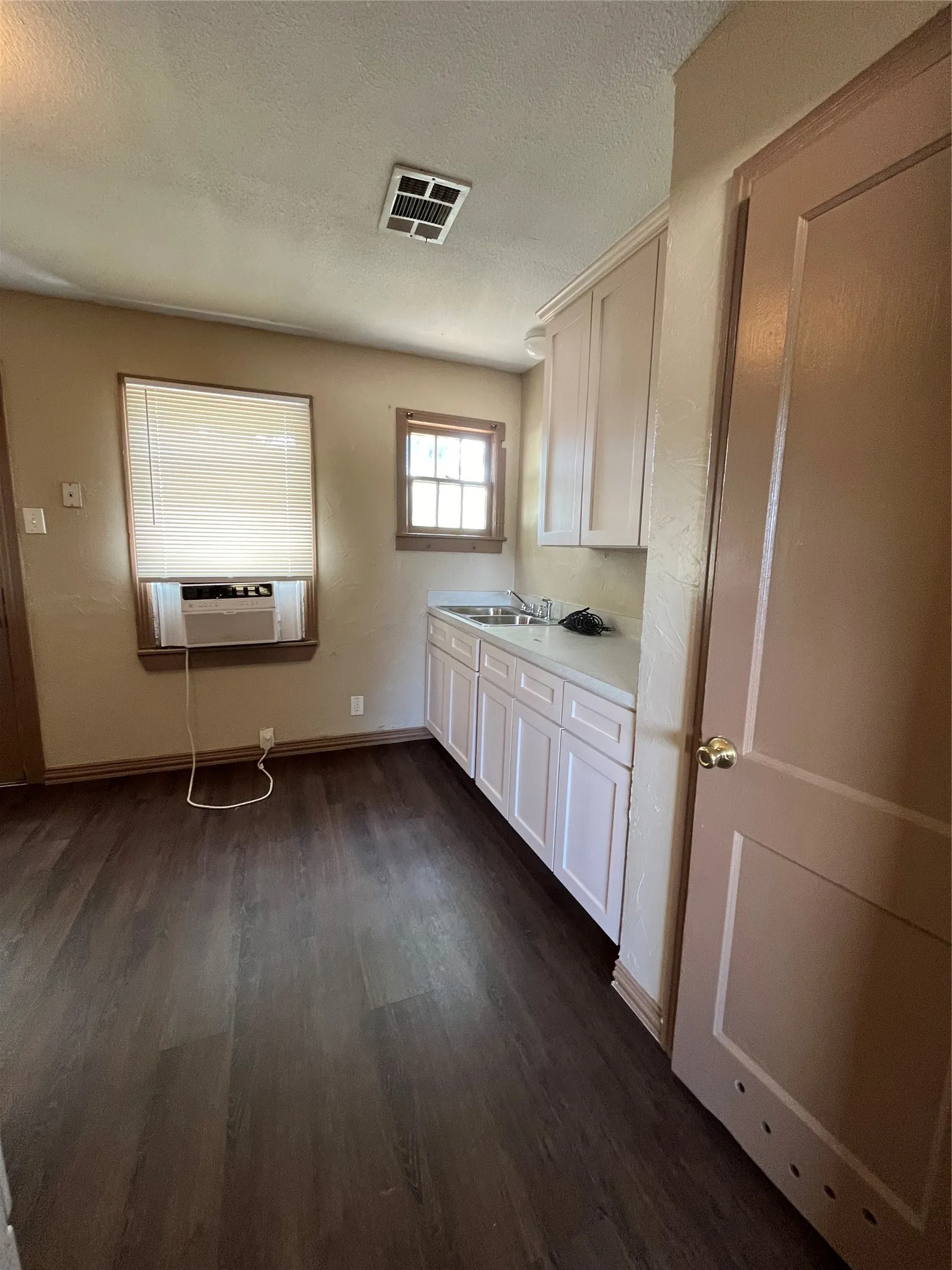 Kitchen with white cabinets, sink, a textured ceiling, cooling unit, and dark hardwood / wood-style flooring