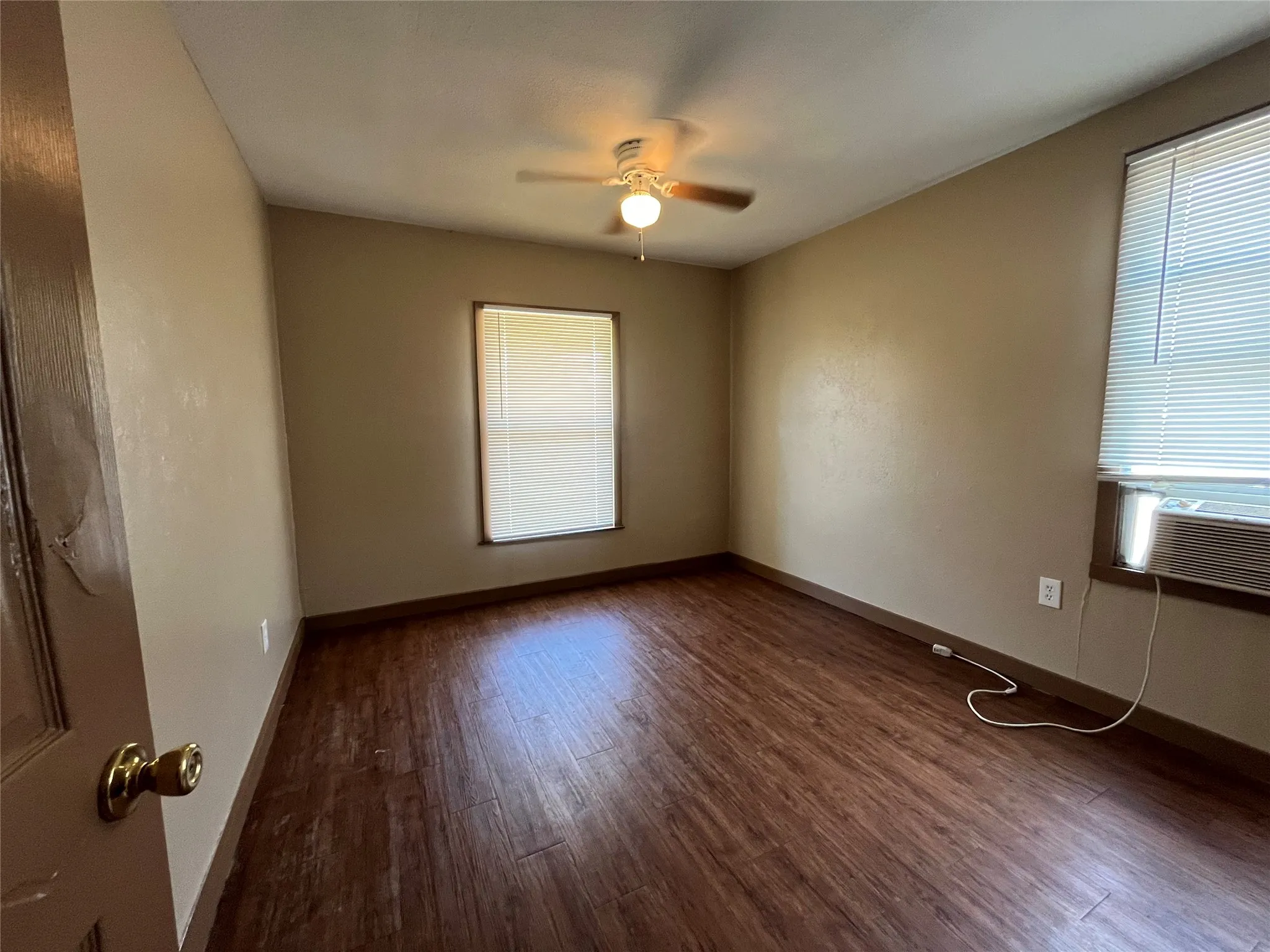 Empty room with ceiling fan, dark hardwood / wood-style floors, and cooling unit