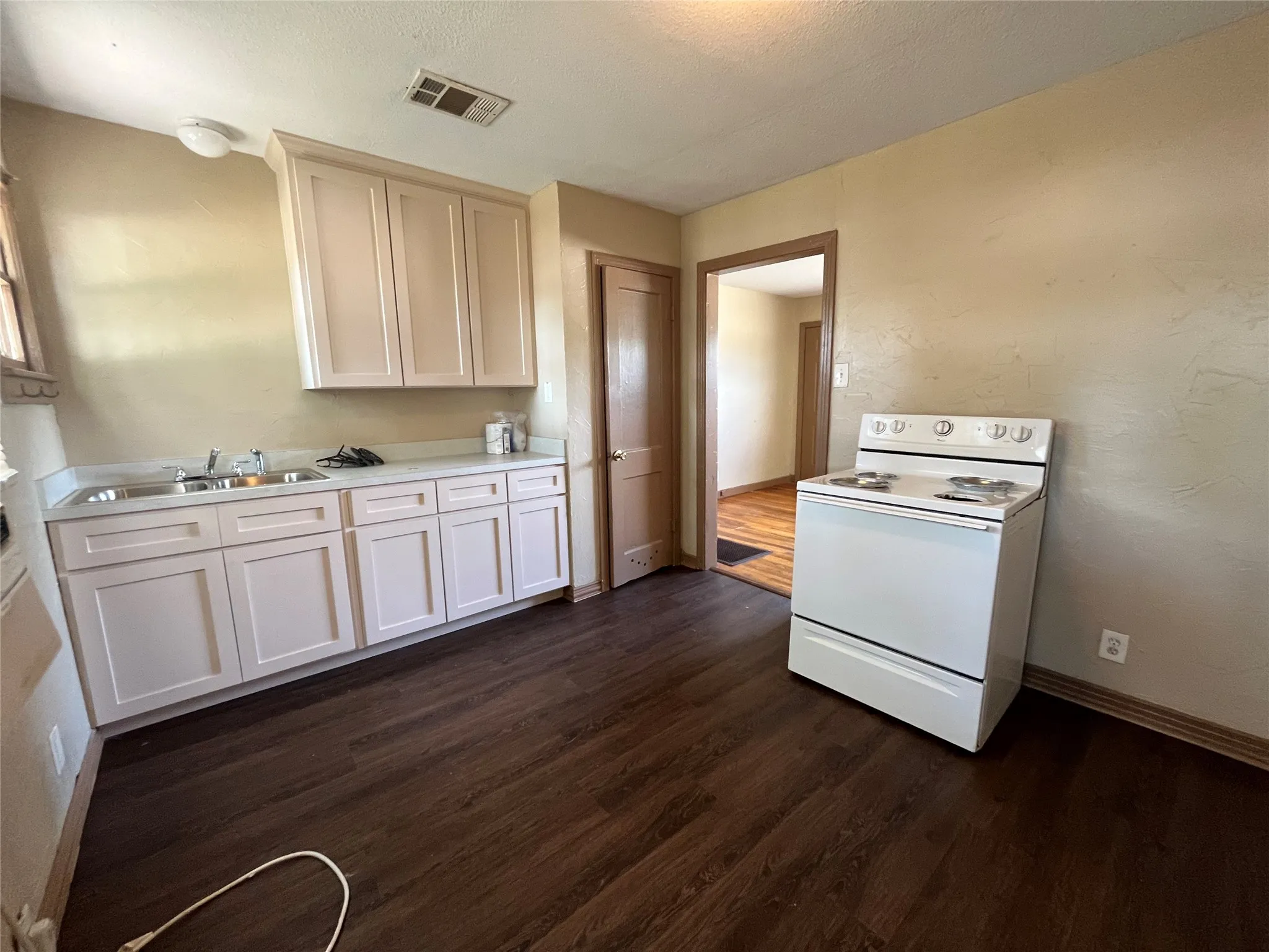 Kitchen with white electric range, dark hardwood / wood-style flooring, and sink