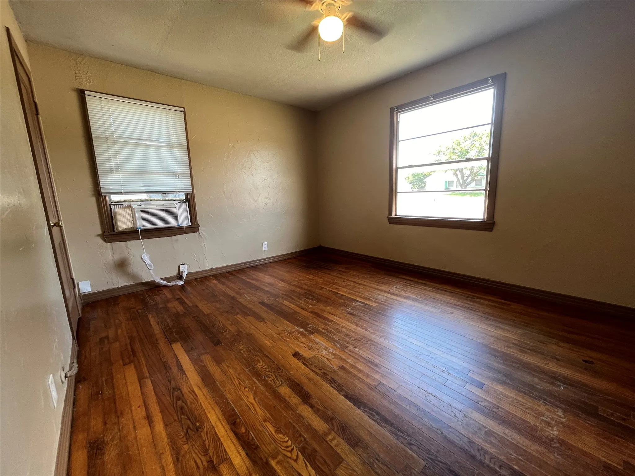 Unfurnished room featuring cooling unit, ceiling fan, and dark hardwood / wood-style flooring