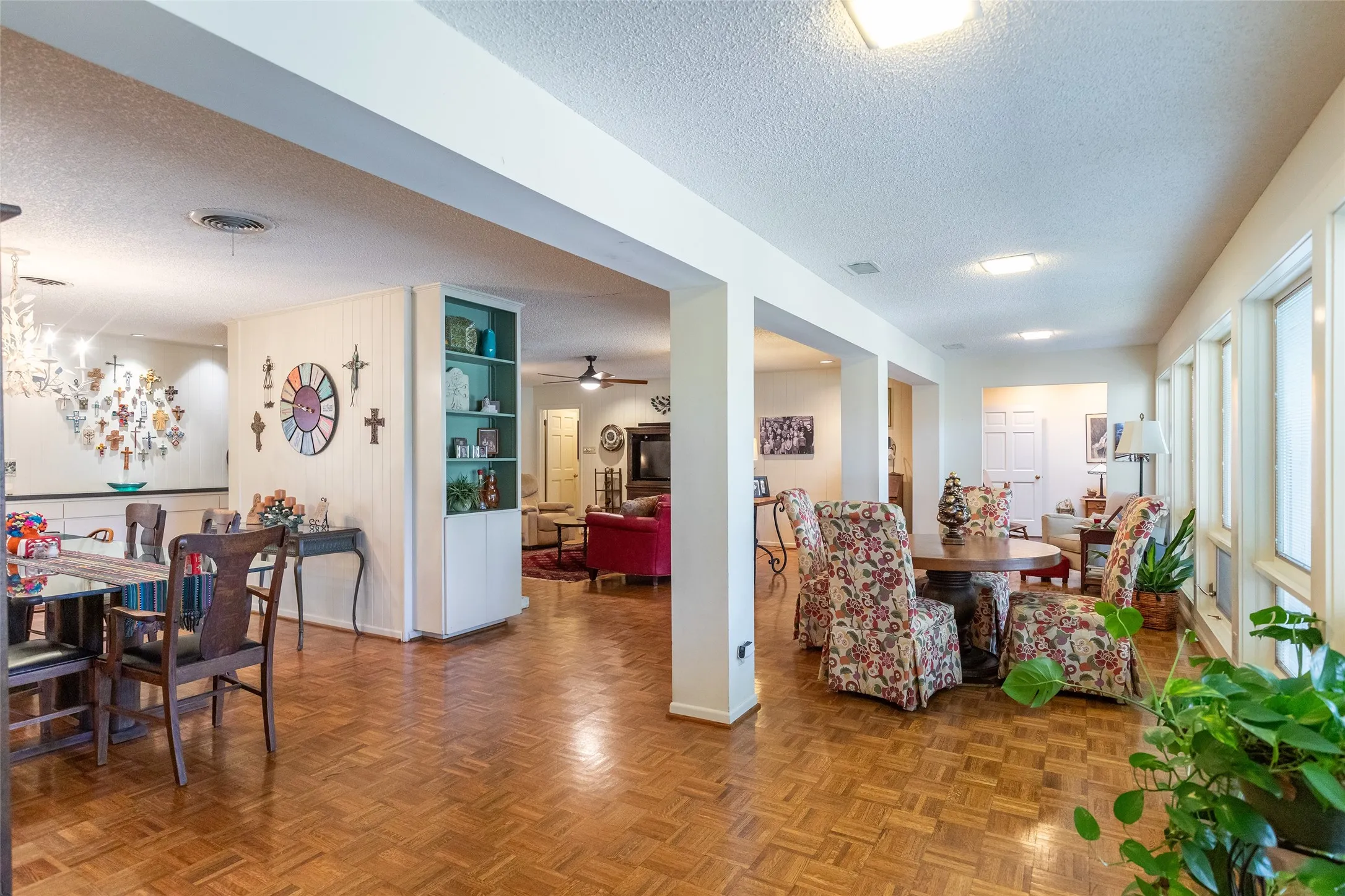 Parquet wood-finish flooring throughout, bright recessed lighting, multiple large windows, and a built-in shelving unit