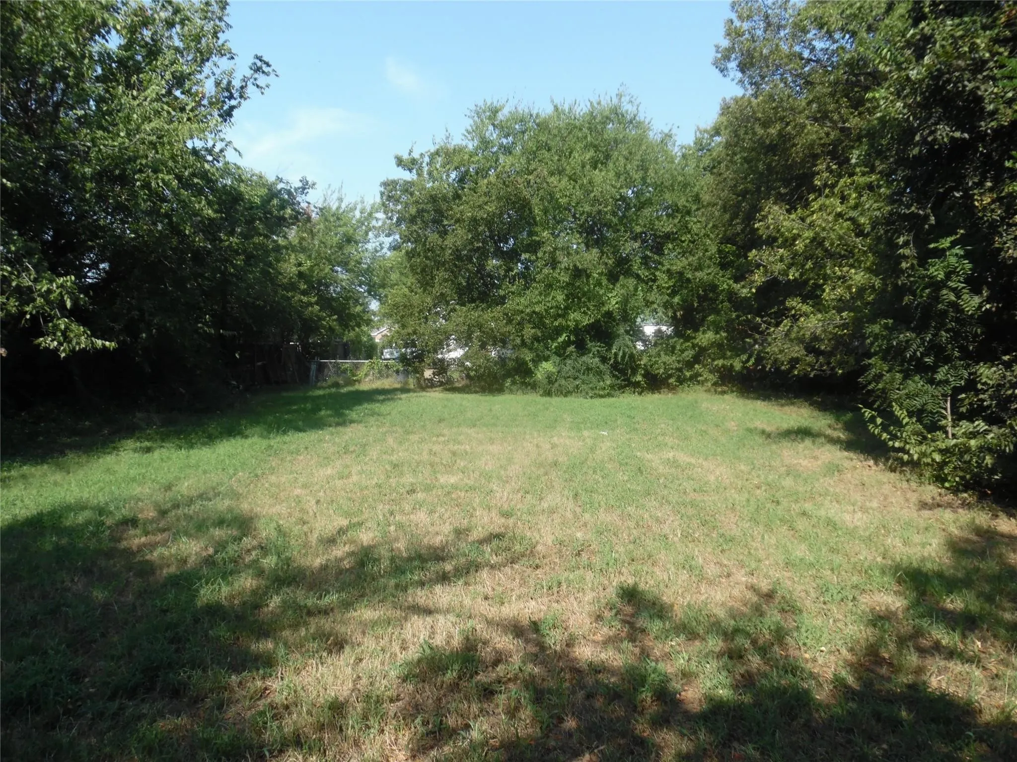 Expansive grass lawn with mature trees providing natural perimeter