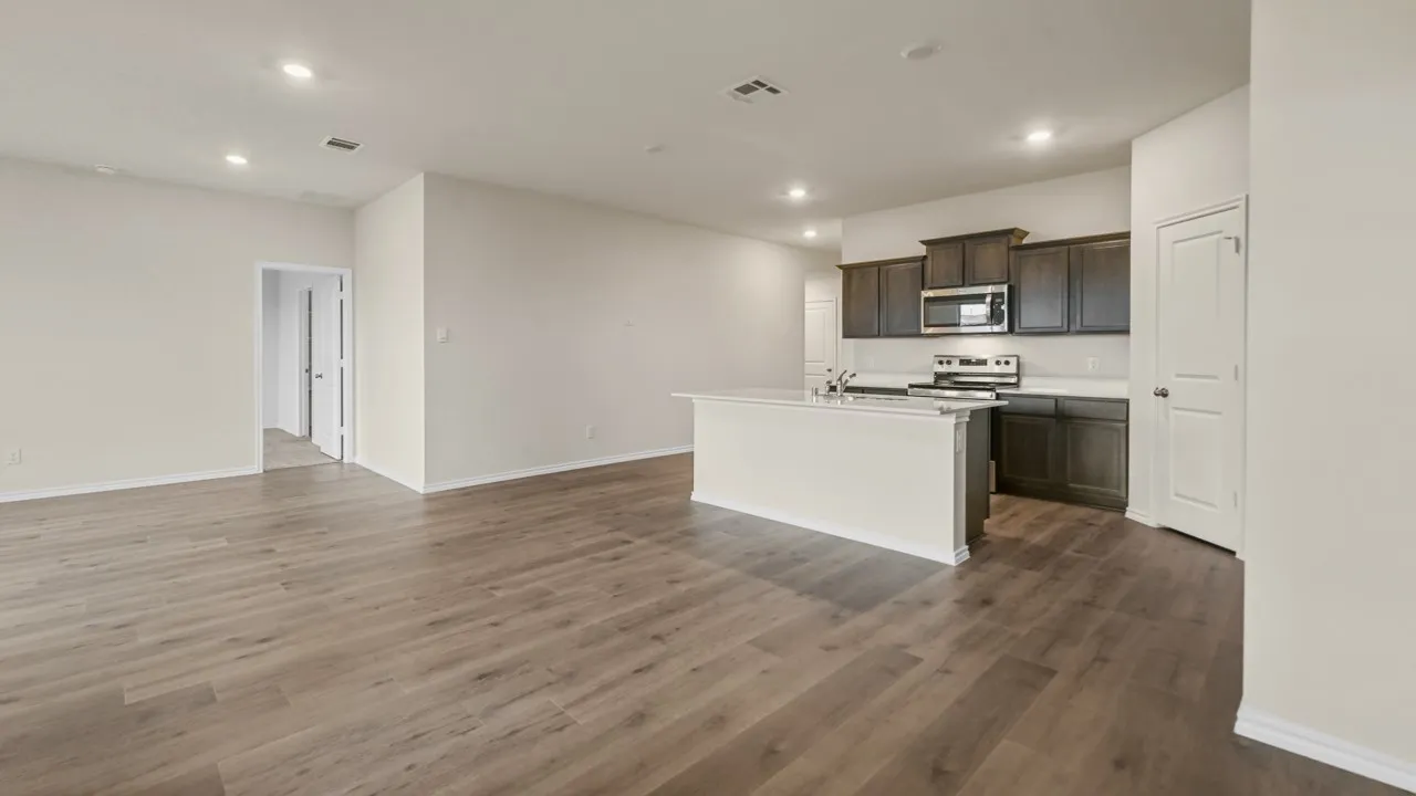 Spacious open-concept living area, wood-finish flooring, recessed lighting, and a kitchen island with a countertop