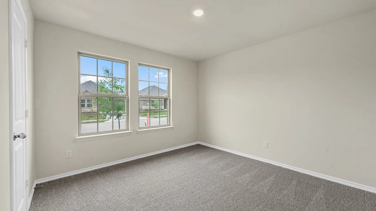 Recessed lighting, two pane windows, neutral wall color, gray patterned carpeting, and a paneled door