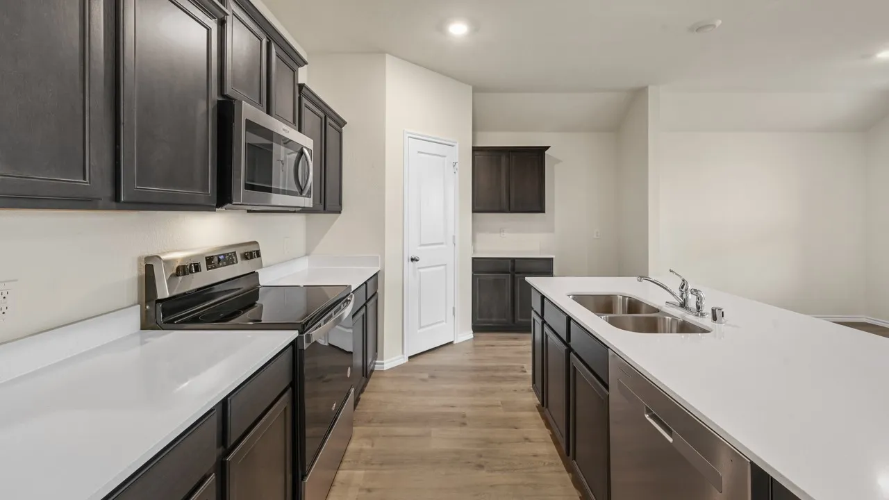Modern kitchen with dark wood-finish cabinetry, stainless steel appliances, solid surface countertops, a dual basin sink, and wood-finish flooring