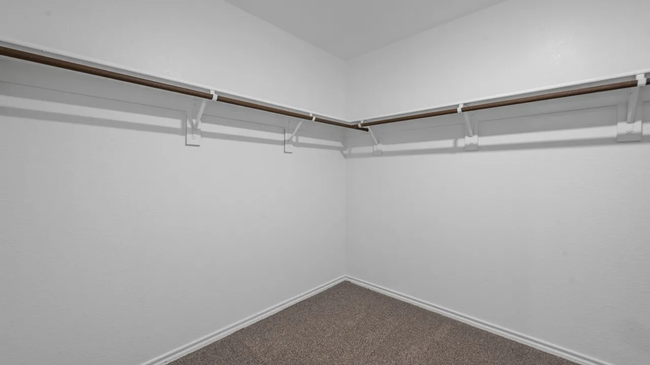 Walk-in closet featuring built-in shelving, hanging rods, and carpet flooring