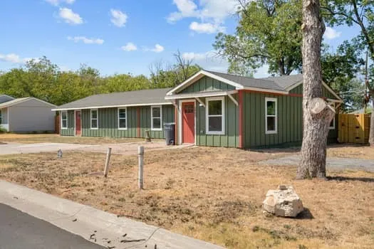 Green board-and-batten siding with white trim, red entry doors, and a light-colored roof