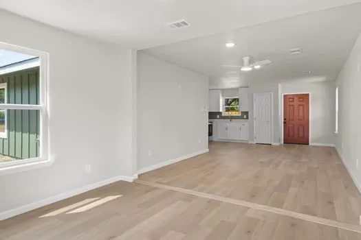Wood-finish flooring throughout, white interior walls, and a ceiling fan with integrated lighting