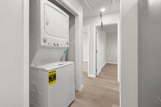 Stackable washer and dryer unit, recessed lighting, and wood-finish flooring