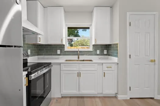Kitchen featuring white cabinetry, light-toned wood-finish flooring, white countertops, and a subway tile backsplash
