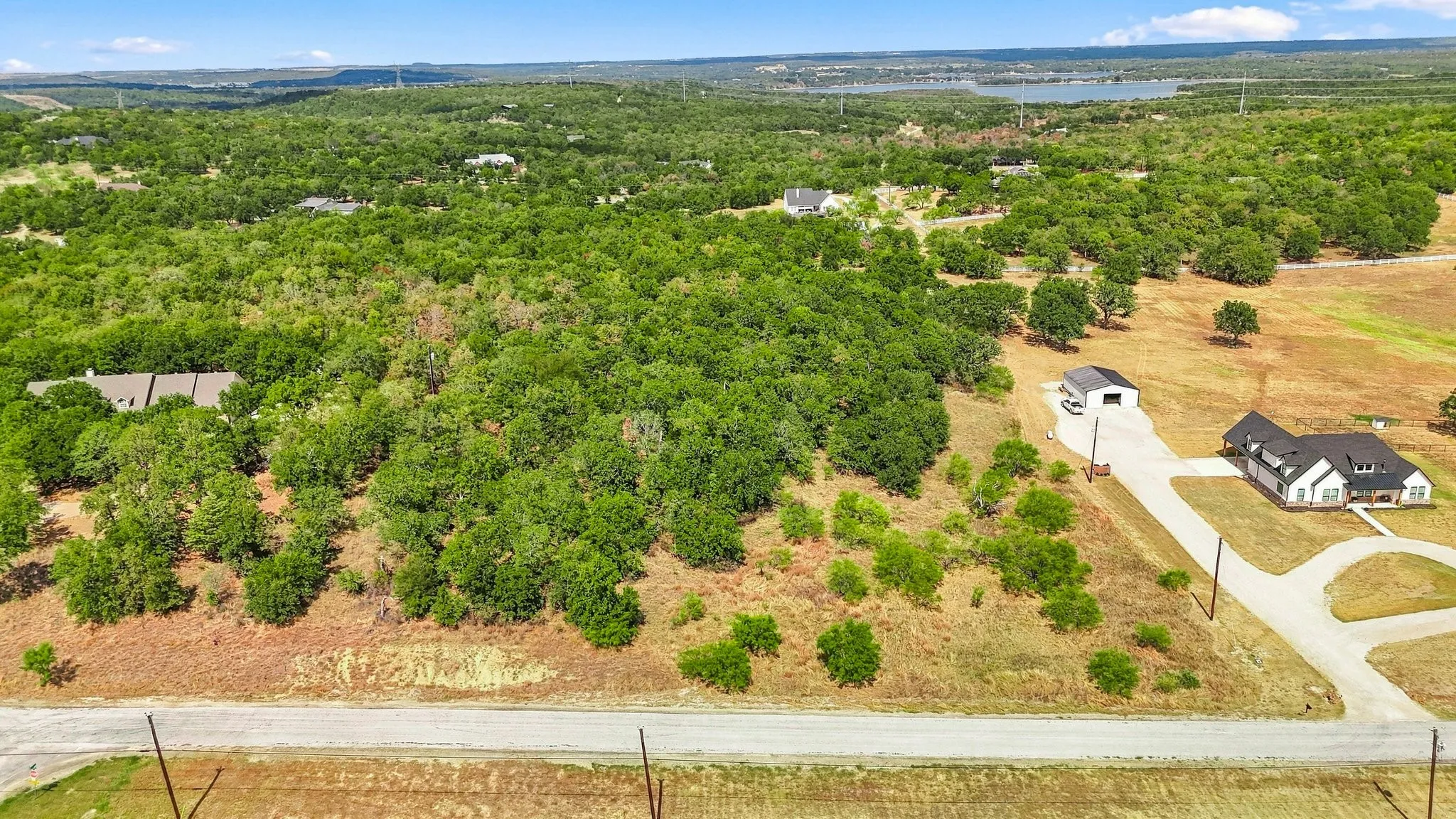 Expansive land parcel featuring dense tree coverage, a clear buildable area, and a paved road frontage
