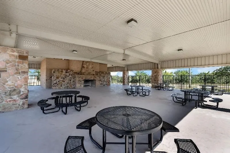 Private Community covered outdoor pavilion featuring a stone fireplace, integrated lighting, and plenty of picnic tables!