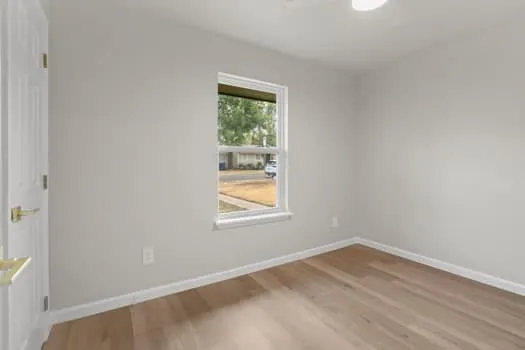 Light wood-finish flooring, single window, white trim, recessed ceiling light, and light-toned walls