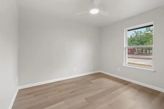 Wood-finish flooring, white walls, and a window with white trim