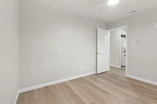 Light-toned wood-finish flooring, white walls, and a ceiling fan with integrated lighting