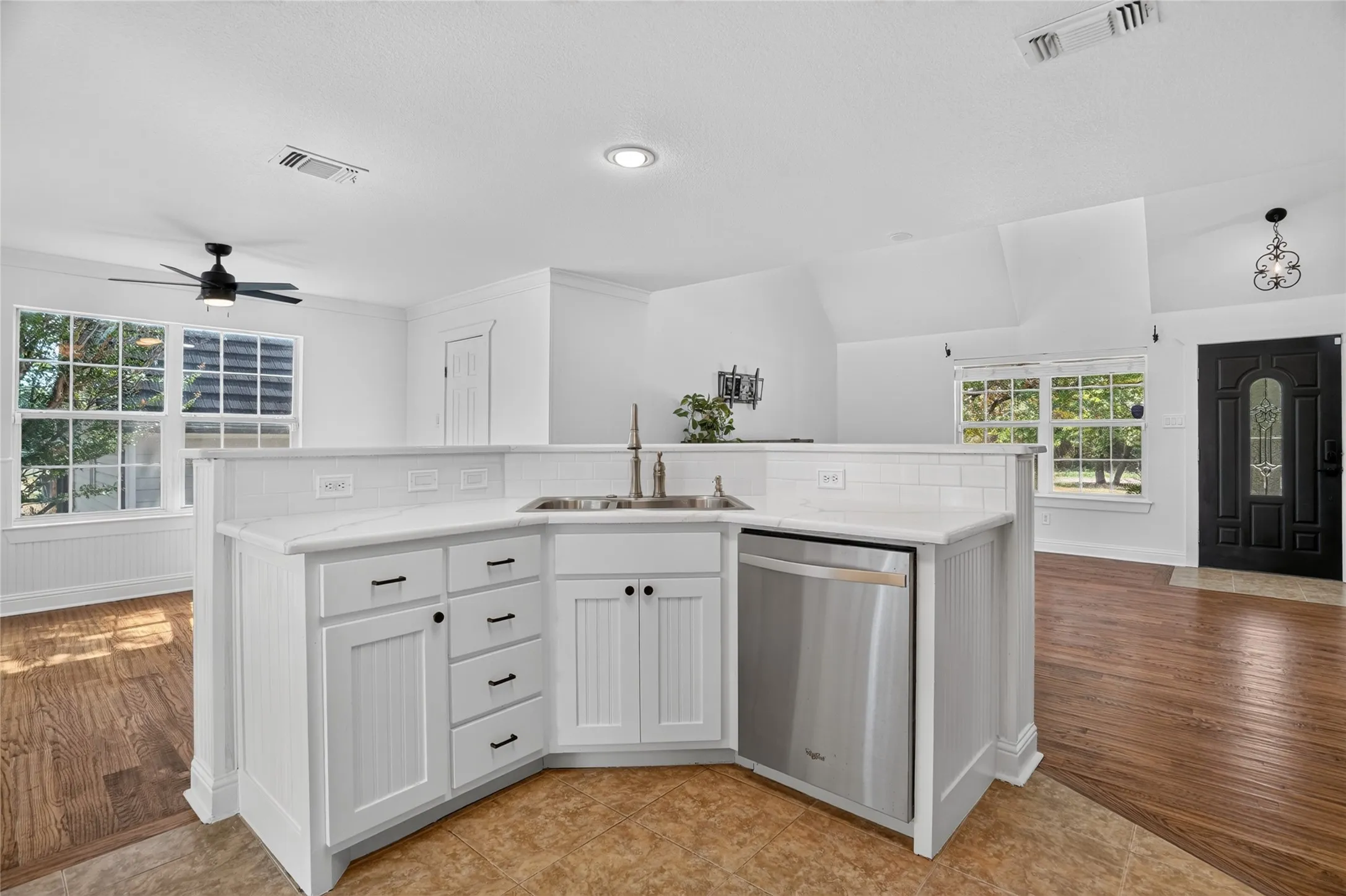 Kitchen island featuring white cabinetry, a stainless steel dishwasher, and a white countertop with a subway tile​​‌​​​​‌​​‌‌​‌‌​​​‌‌​‌​‌​‌​​​‌​​ backsplash