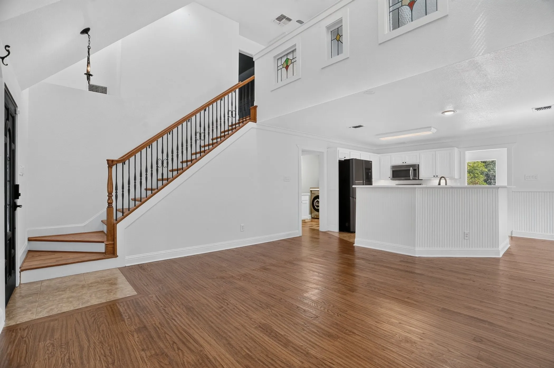 Wood-finish flooring throughout, with a striking wood and wrought iron staircase