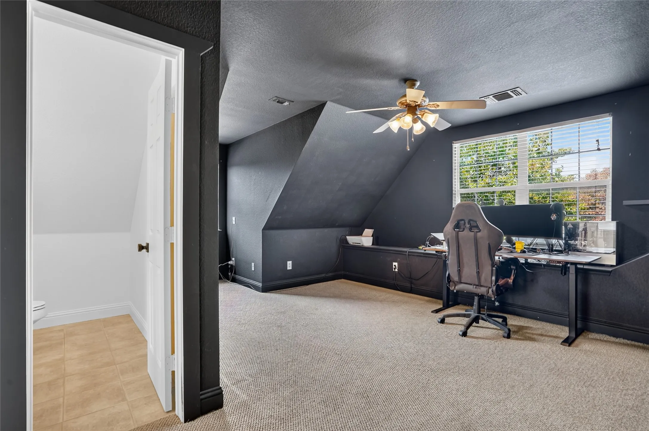 Carpeted room with a ceiling fan, window with blinds, and built-in cabinetry along one wall