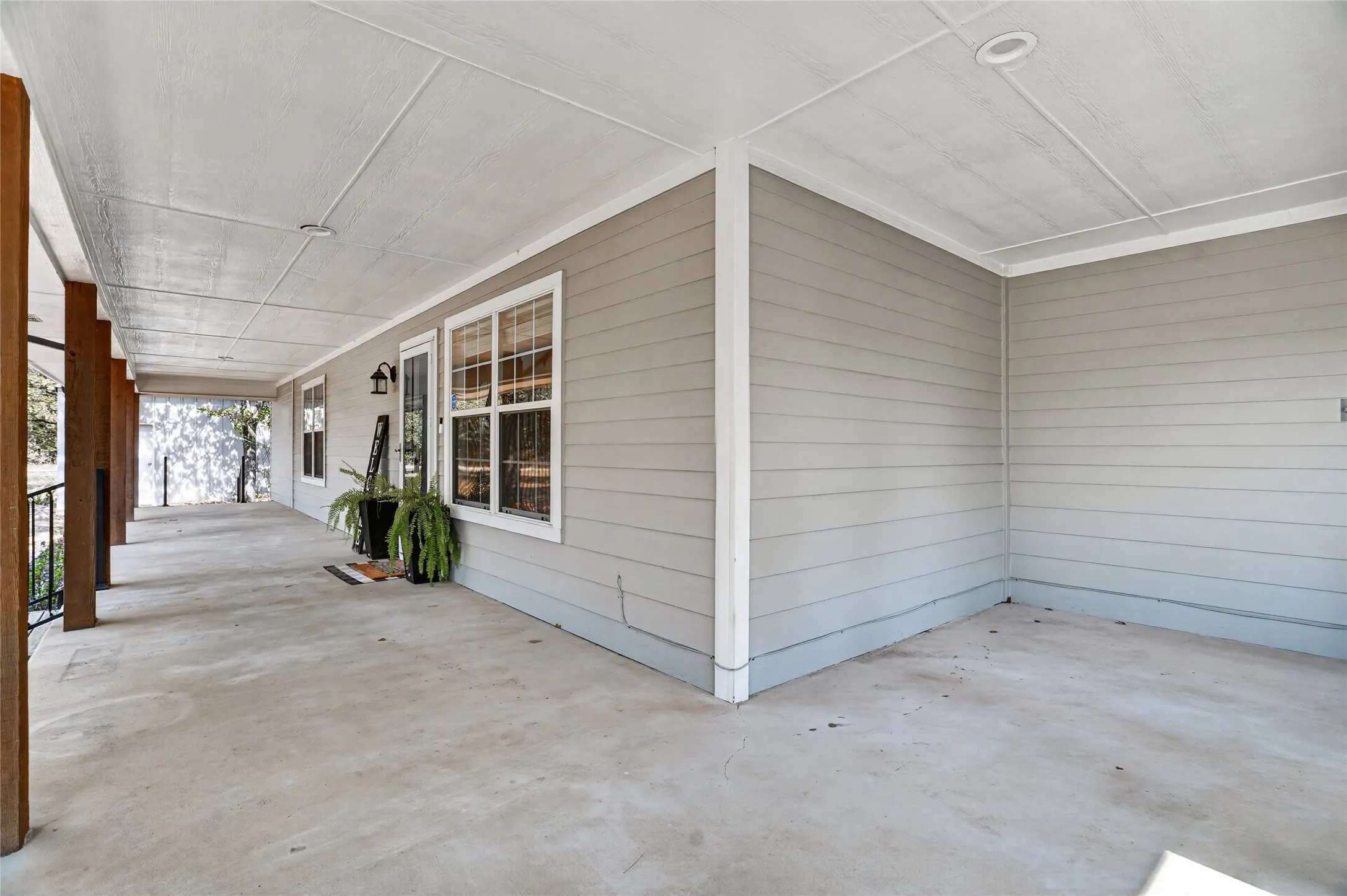 Expansive concrete porch with recessed lighting, wood support columns, and durable siding