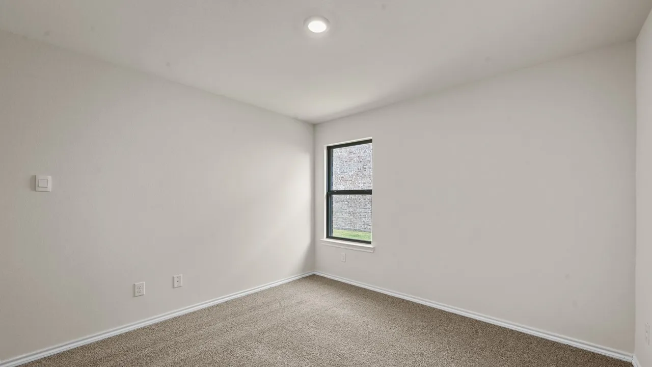 Recessed ceiling lighting, neutral carpet flooring, and a single window with dark framing