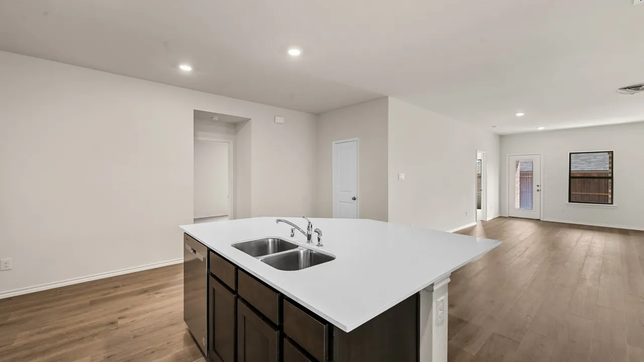 Kitchen island with dual stainless steel sink, white countertop, and dark wood-finish cabinetry
