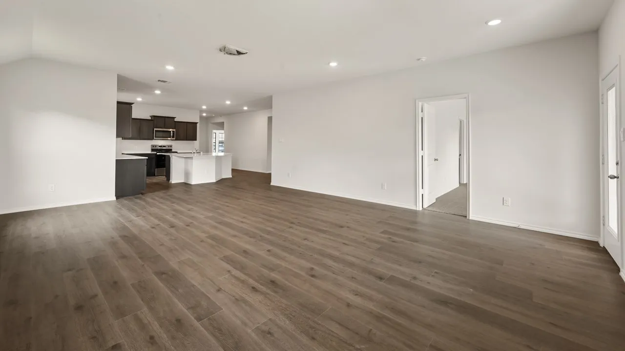 Open-concept layout featuring wood-finish flooring, recessed lighting, and a kitchen with dark cabinetry and stainless steel appliances