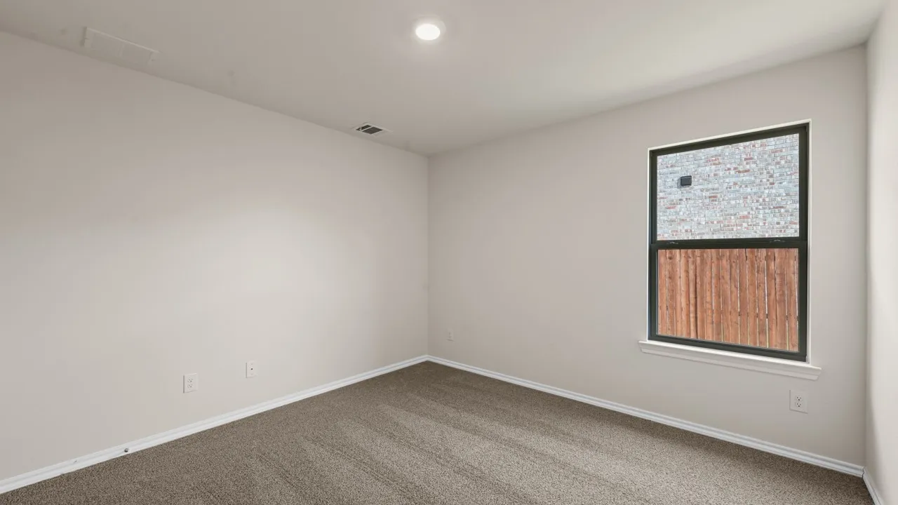 Neutral wall paint, recessed ceiling lighting, light brown carpeting, single window with dark framing, and white window trim