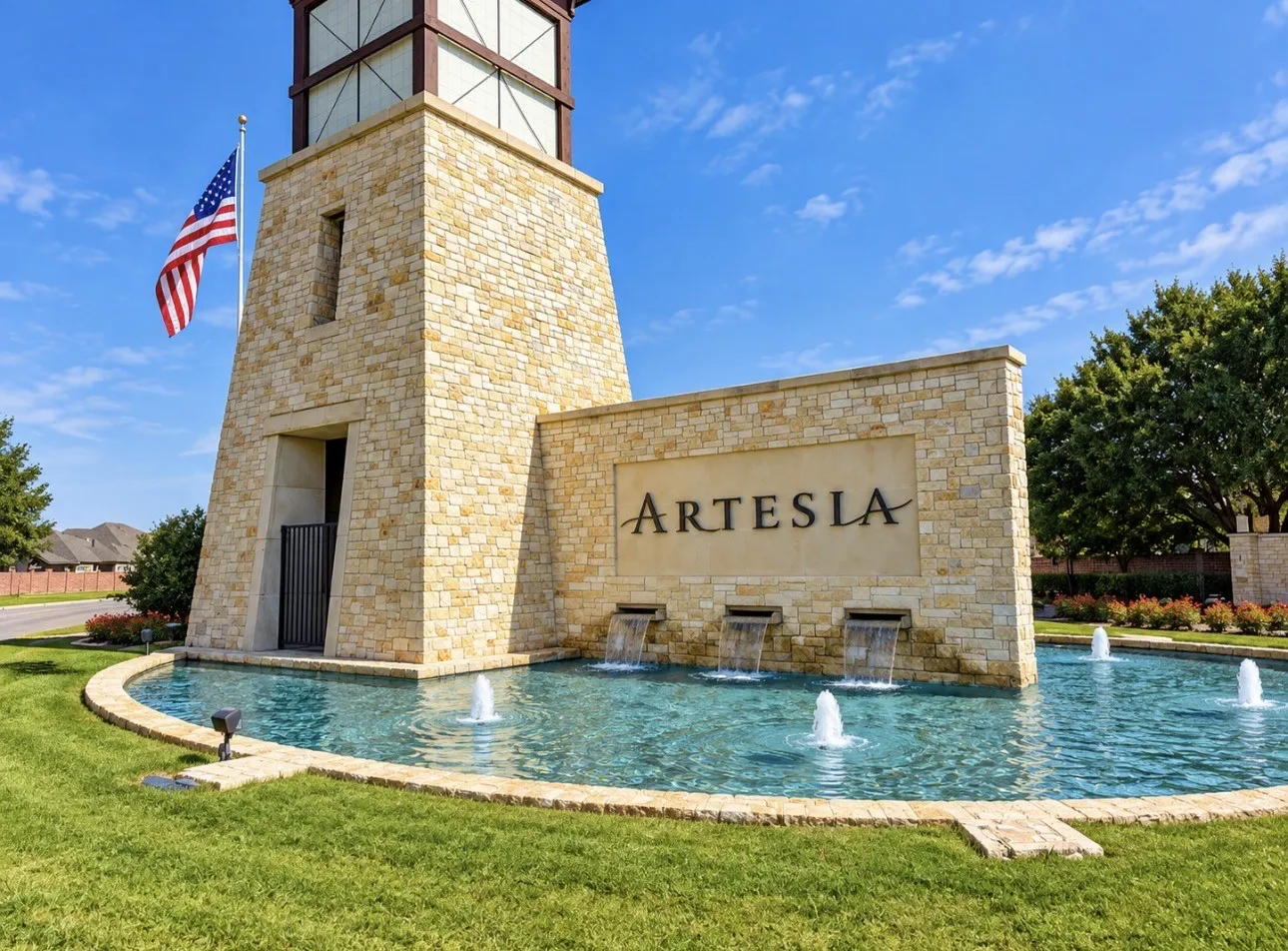 Stone entry monument with a prominent tower, integrated water features, and a clear community sign
