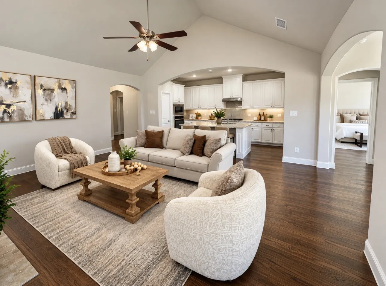 Vaulted ceiling with ceiling fan, dark wood-finish flooring, arched doorways, white kitchen cabinetry, and built-in kitchen appliances