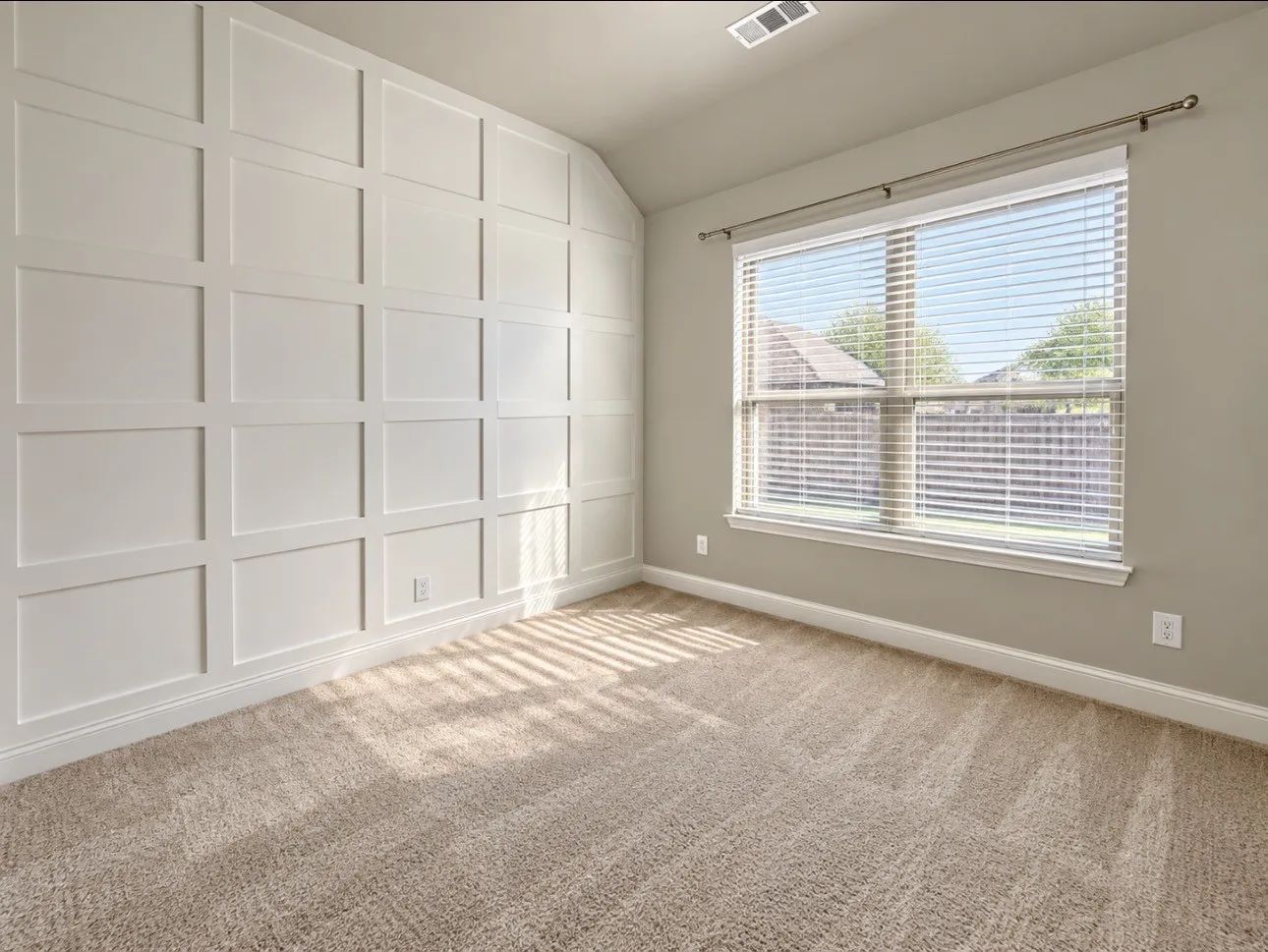 Accent wall with grid paneling, neutral carpeting, and a large window with blinds