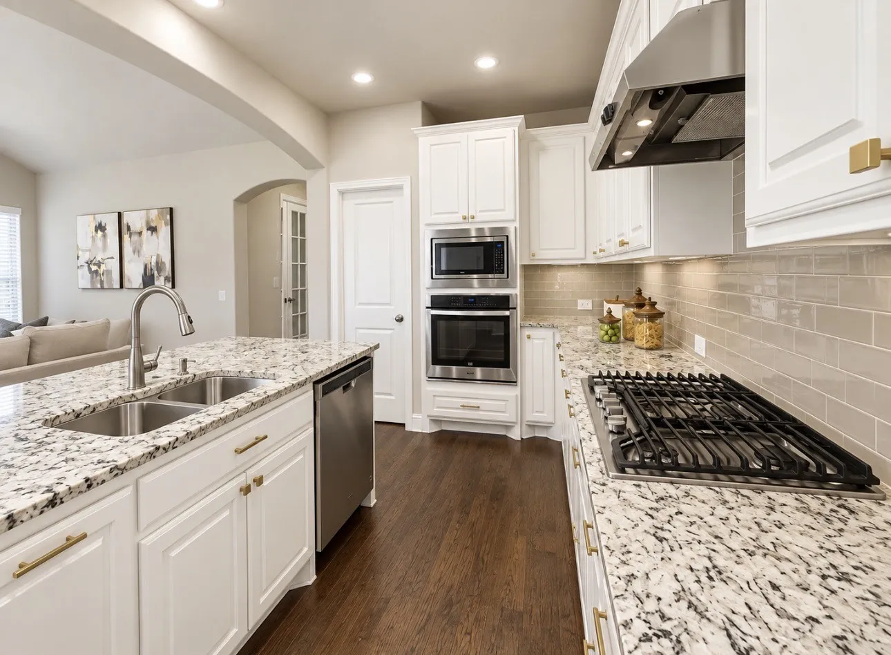 Kitchen featuring white cabinetry, built-in stainless steel appliances, a gas cooktop, light-toned subway tile backsplash, and speckled countertops