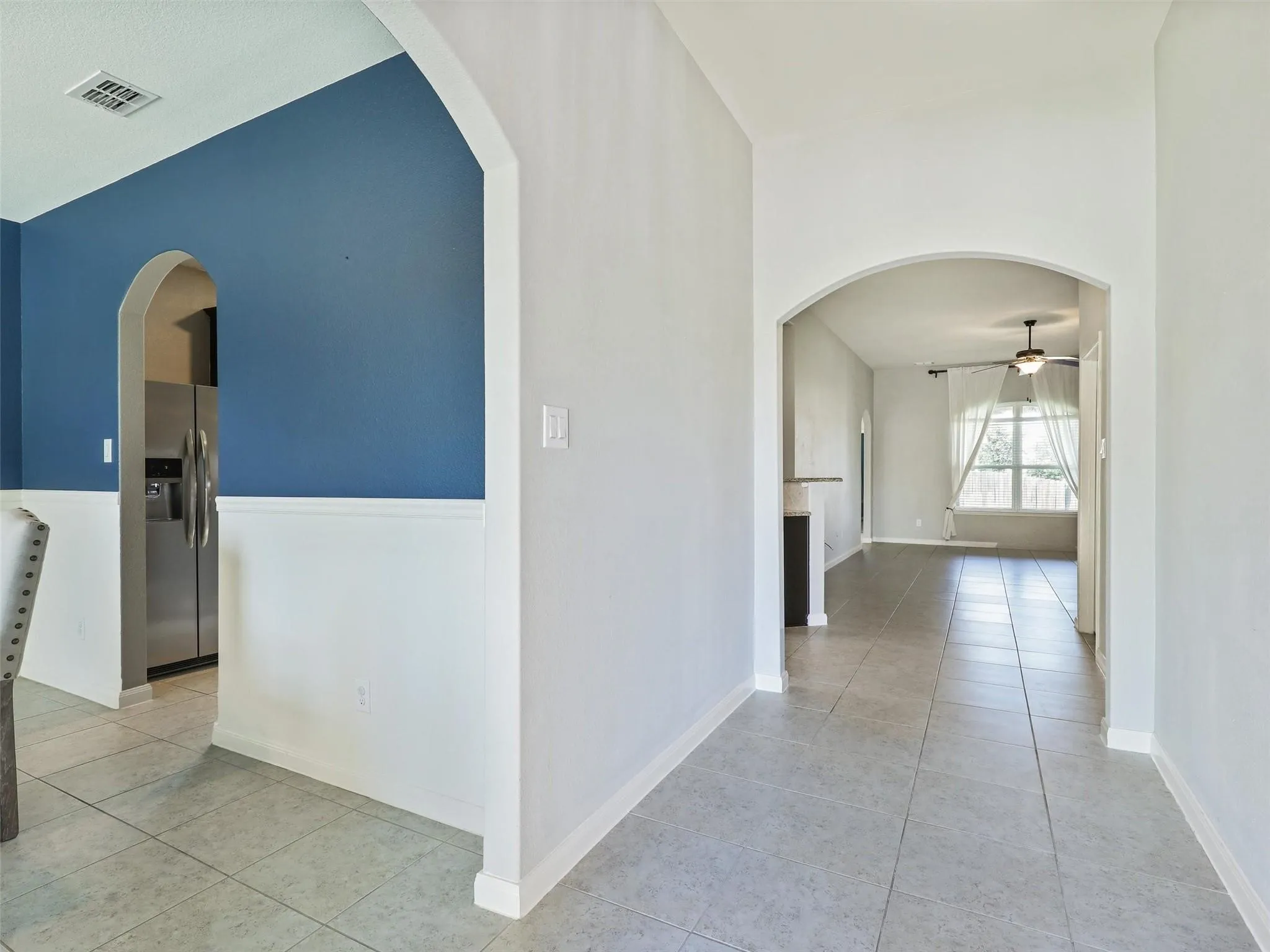 Arched doorways, tile flooring, two-tone wall treatment, and a ceiling fan