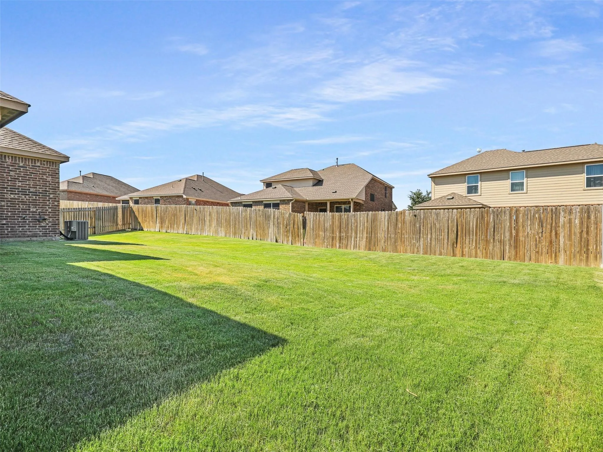 Expansive green lawn with a wood privacy fence