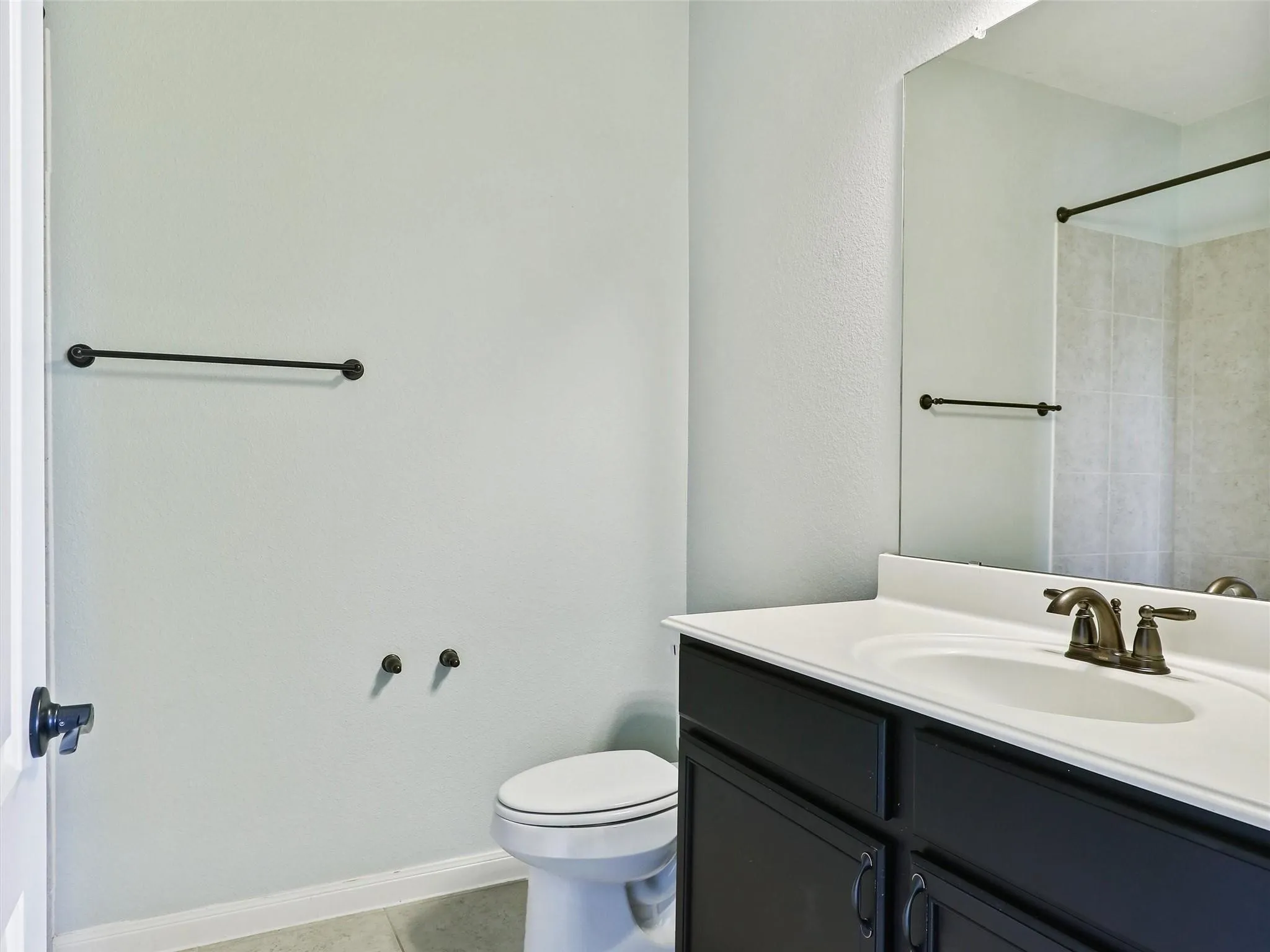 Vanity with dark cabinetry and an integrated sink, bronze-finish faucet, and a large wall-mounted mirror