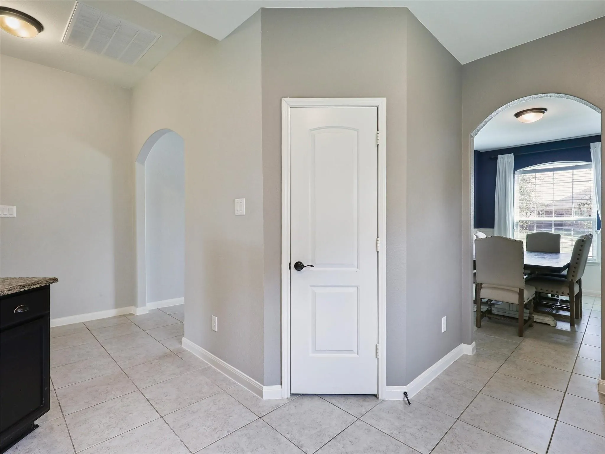 Arched doorways, tile flooring, interior solid door, recessed lighting, and built-in cabinetry with stone countertop