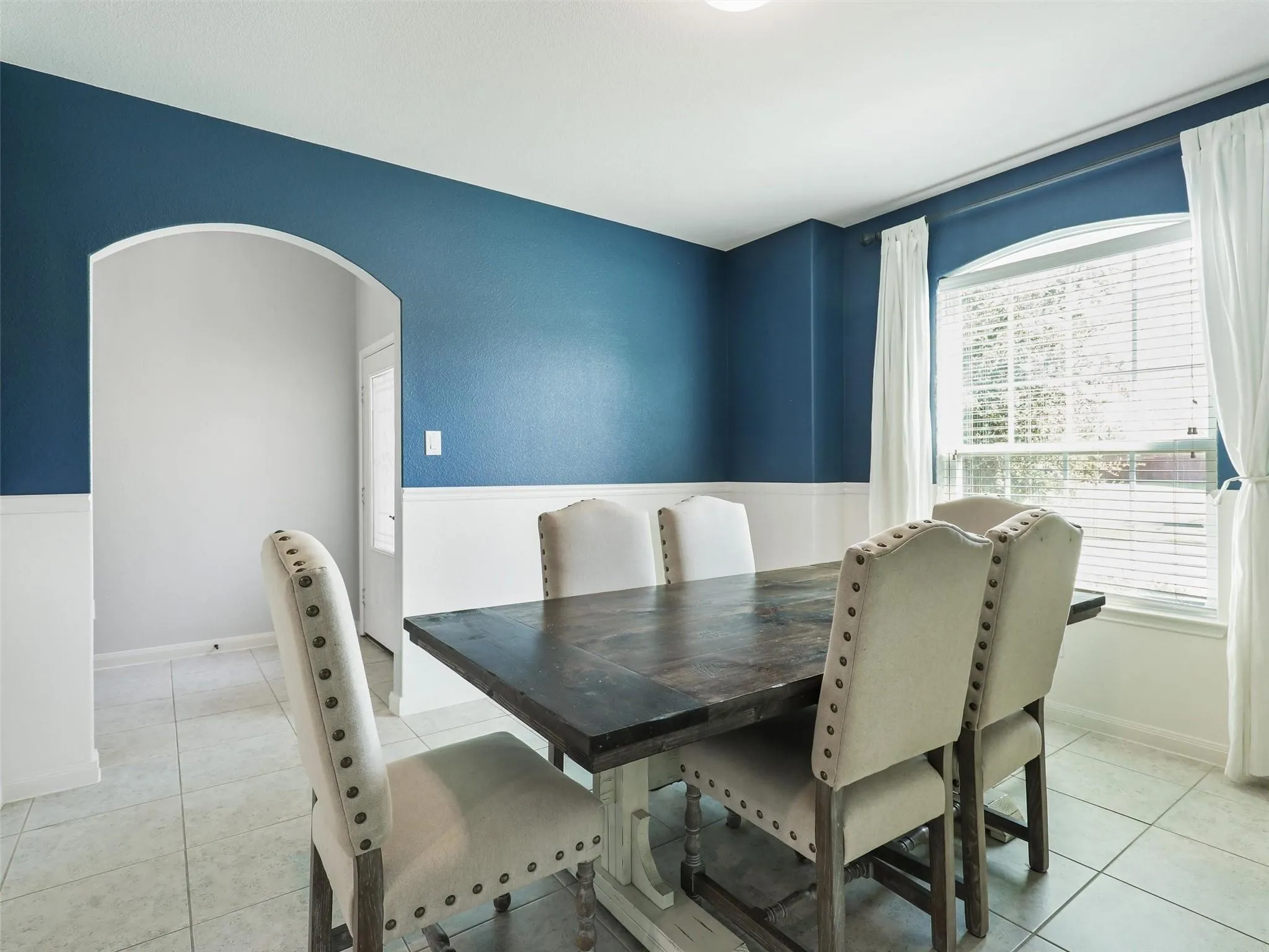 Tile flooring paired with wainscoting and an arched doorway