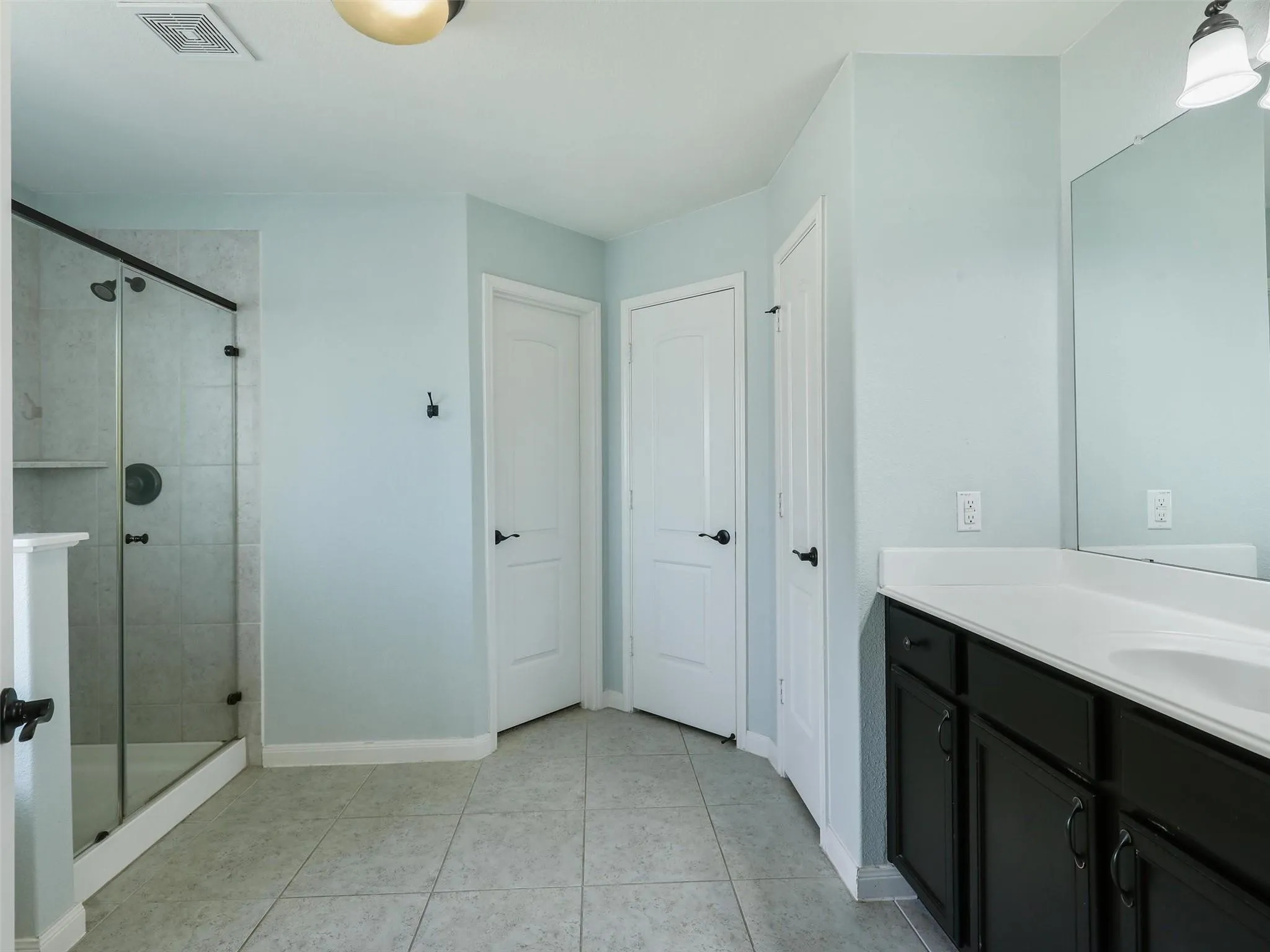 Tiled flooring complemented by a glass-enclosed shower with a built-in shelf
