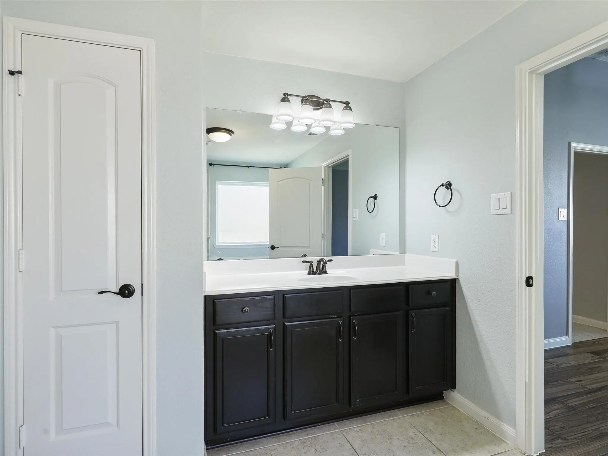 Vanity featuring a white countertop, undermount sink, and dark wood-finish cabinetry