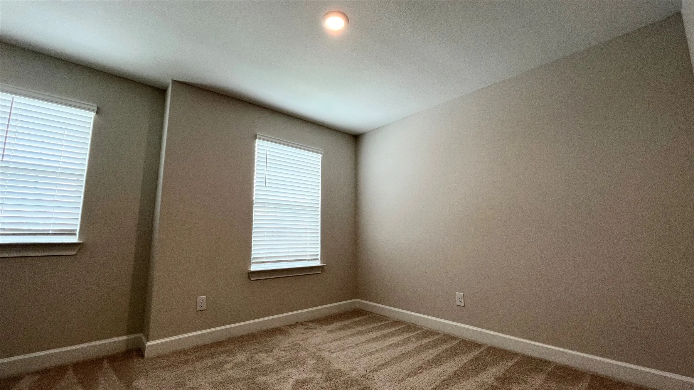 Wall-to-wall carpeting, dual windows with blinds, recessed ceiling light, and neutral wall tones