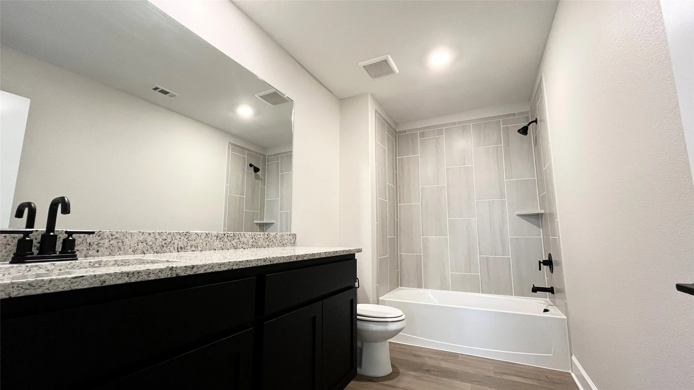 Vanity with a granite countertop, matte black fixtures, and integrated sink