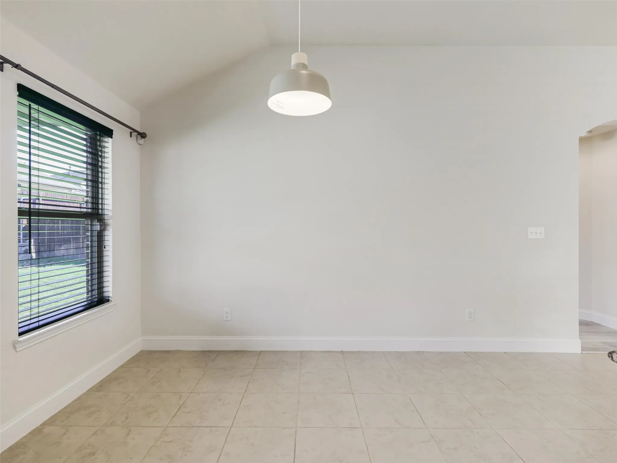 Vaulted ceiling, recessed lighting, tile flooring, window with blinds, and arched doorway