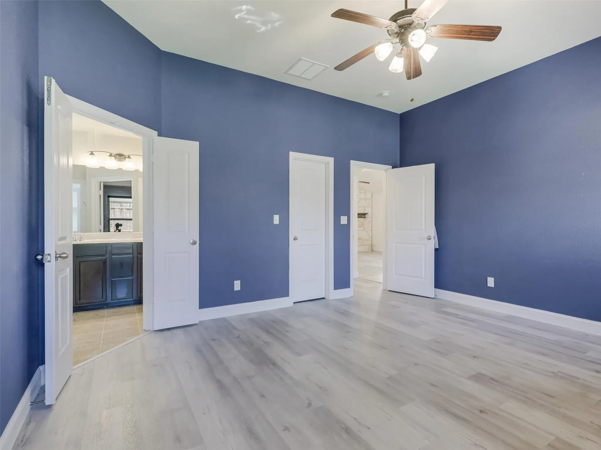 Vaulted ceilings with a ceiling fan, light wood-finish flooring, and white trim