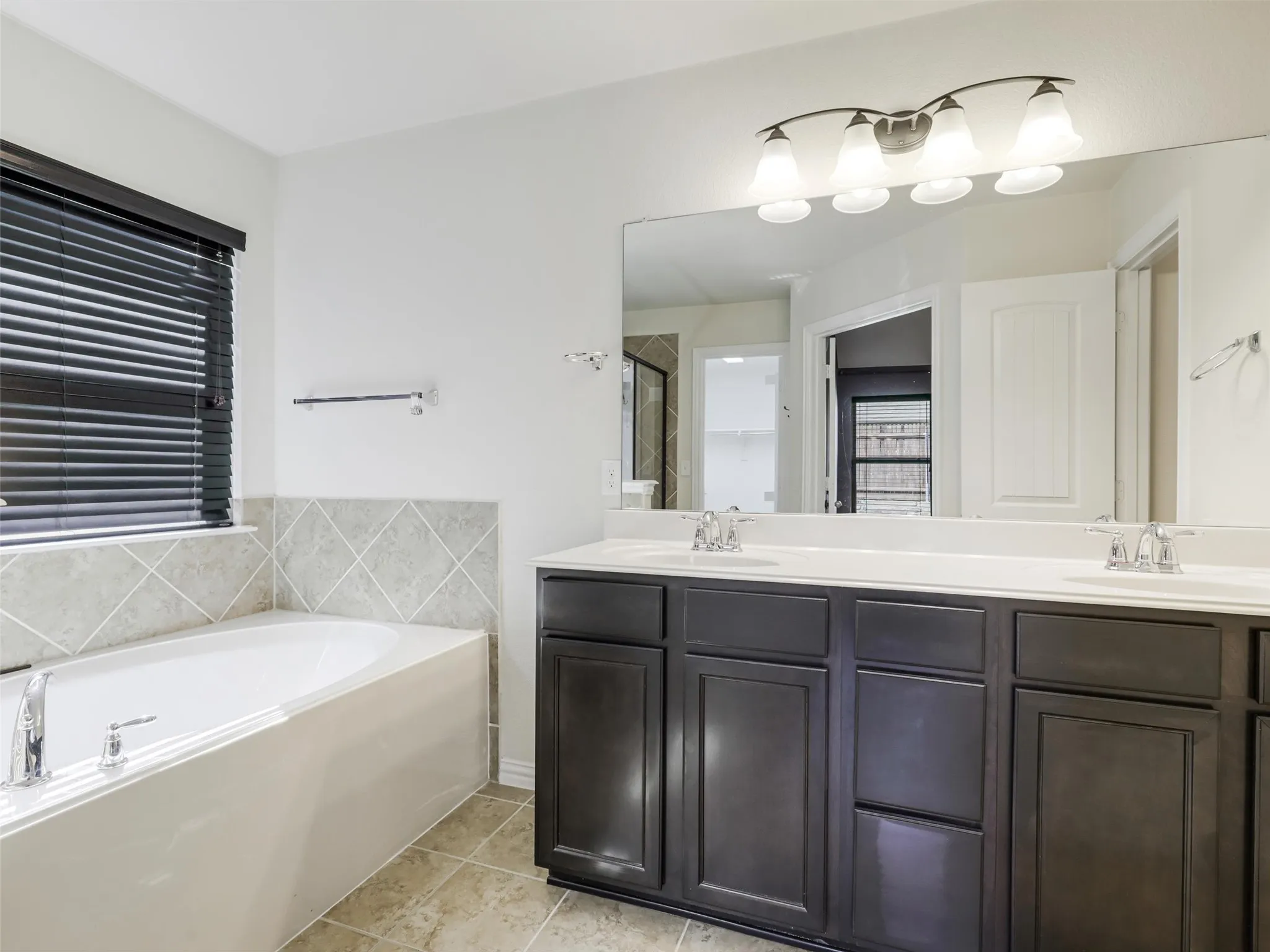 Dual vanity with dark wood-finish cabinetry, integrated white sinks, and chrome fixtures
